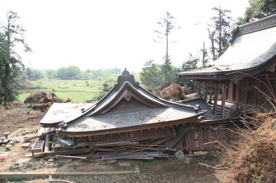 竜巻により倒壊し、屋根が地面まで落ちている神社の写真