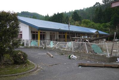 園庭の遊具が壊れたり柵が変形している被災した筑波幼稚園の写真