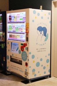 青い羽基金のロゴが側面に描かれた寄附型自動販売機の写真