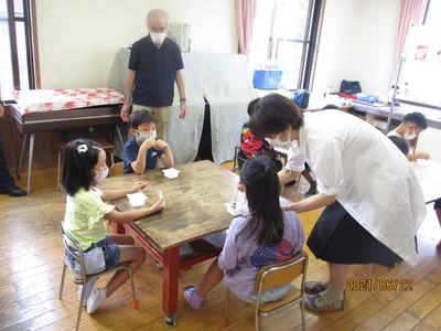 久保先生が子ども達にフルーチェを配っている写真