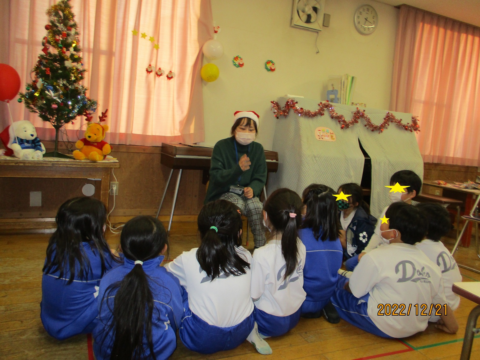 クリスマスイベントで、クリスマスのお話を聞く子供たち