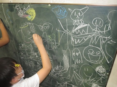 黒板一面に描かれた子供たちのお絵描きの写真