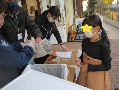 児童館の玄関先で焼き芋を配っている様子の写真