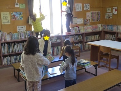 本の整理整頓をしながら図書室の掃除している子どもたちの写真