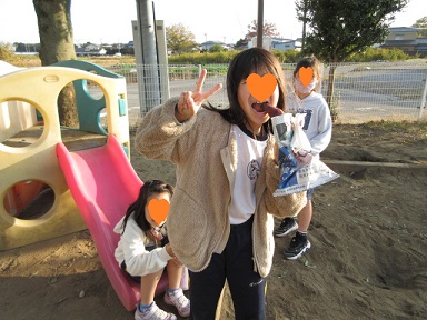 公園で焼き芋を食べている女性と子供たちの写真