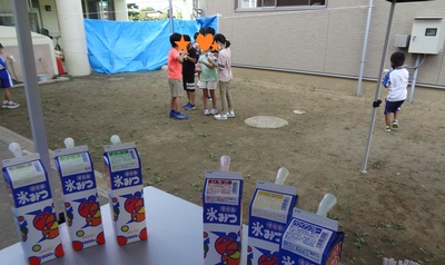 机の上に置かれている6種類のシロップと、子供たちが集まってかき氷を食べている様子の写真