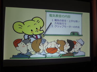 関東電気保安協会のキャラクター、エレちゃんが電気教室の内容を説明している様子がスクリーンに映っている写真