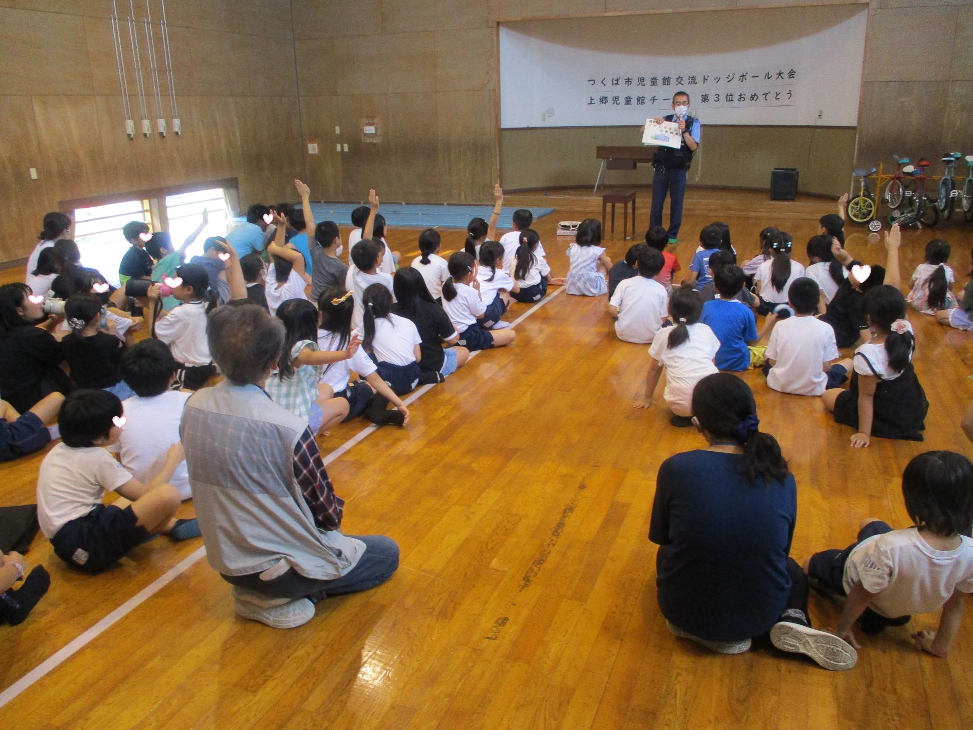 お巡りさんの質問に手を挙げて答える子どもたち