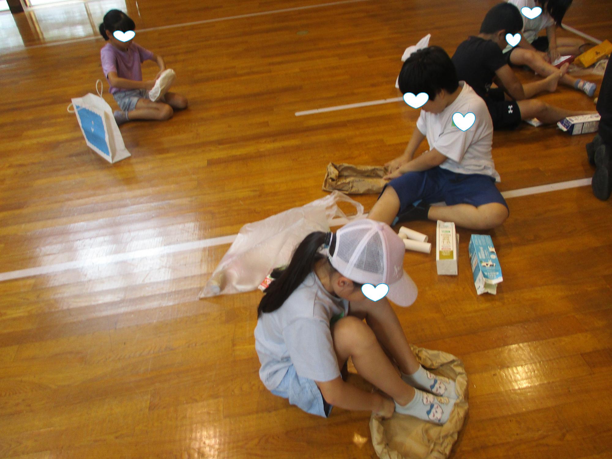紙袋を強く巻くため足で踏む参加者