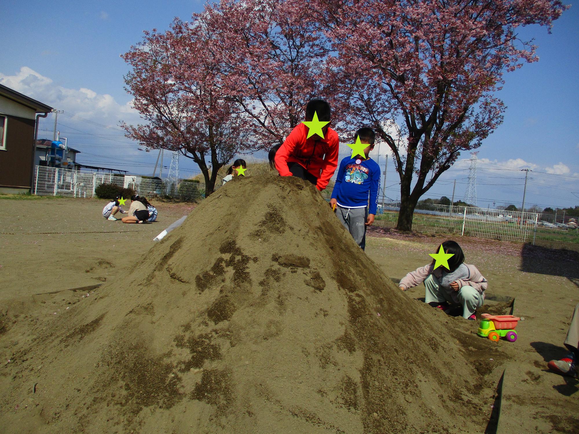 砂場の大きな山に登る子どもたち