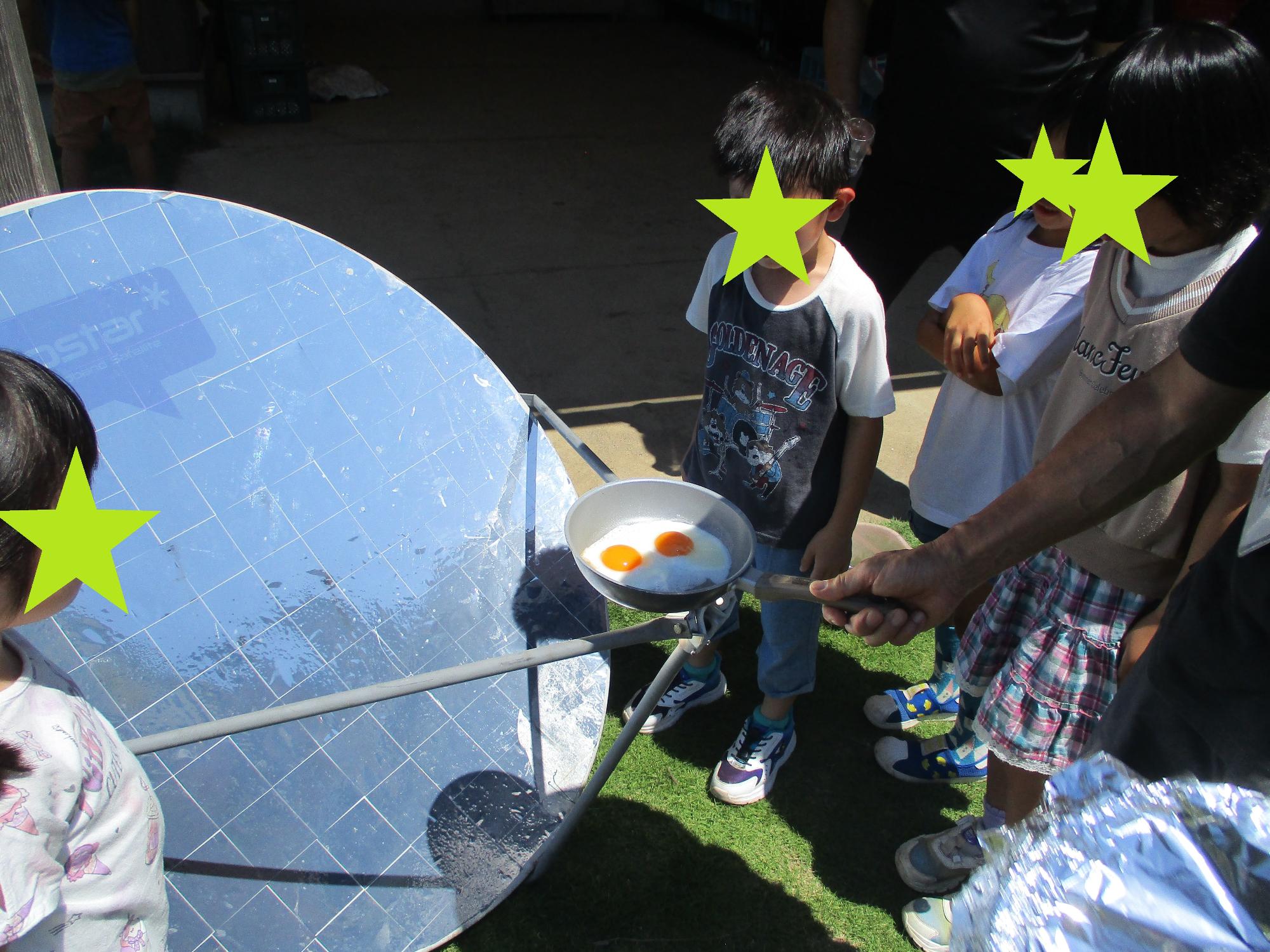 太陽光で卵が焼ける様子を観察する子どもたち
