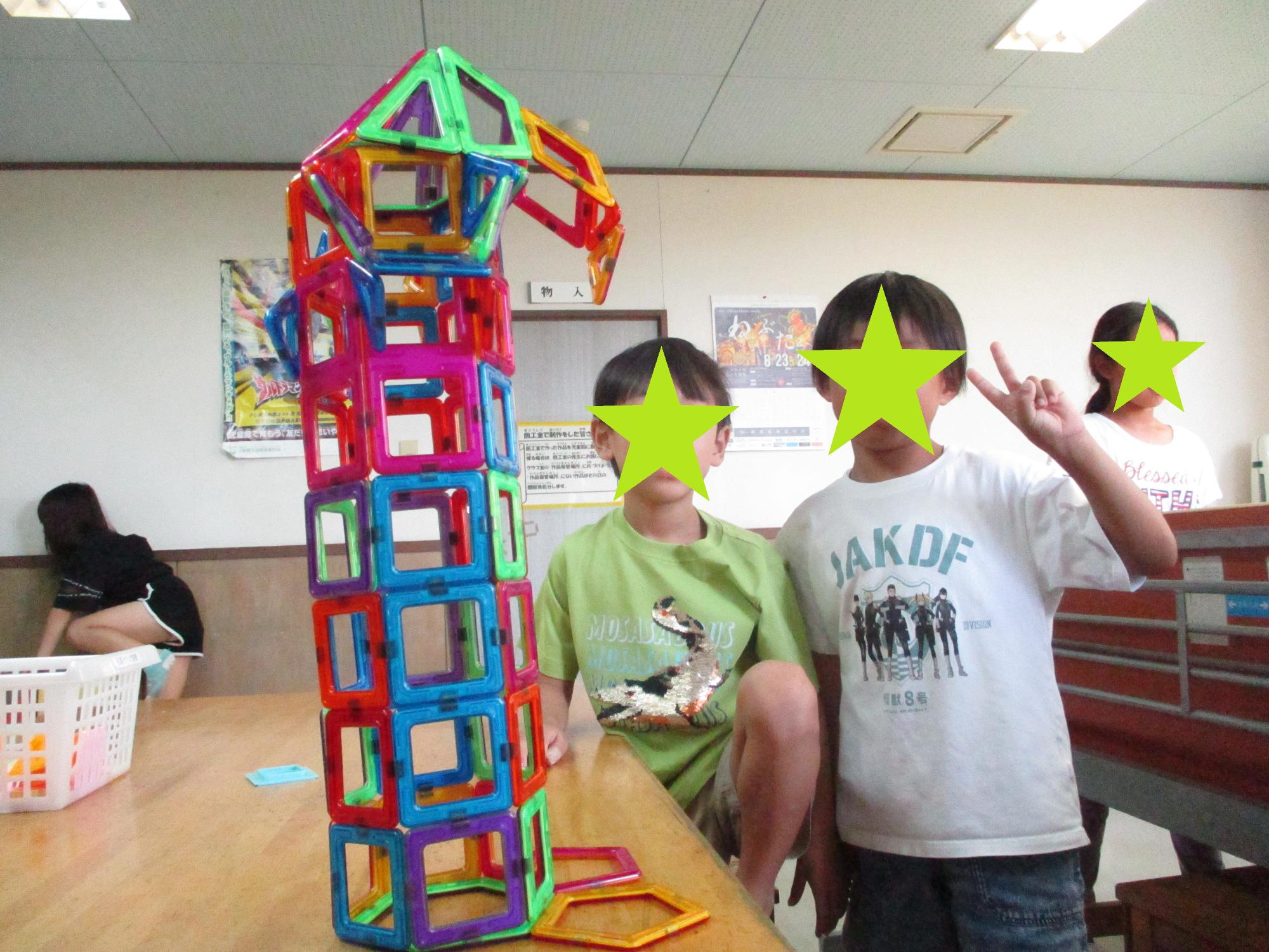 マグネットブロックで作った作品とピースする子