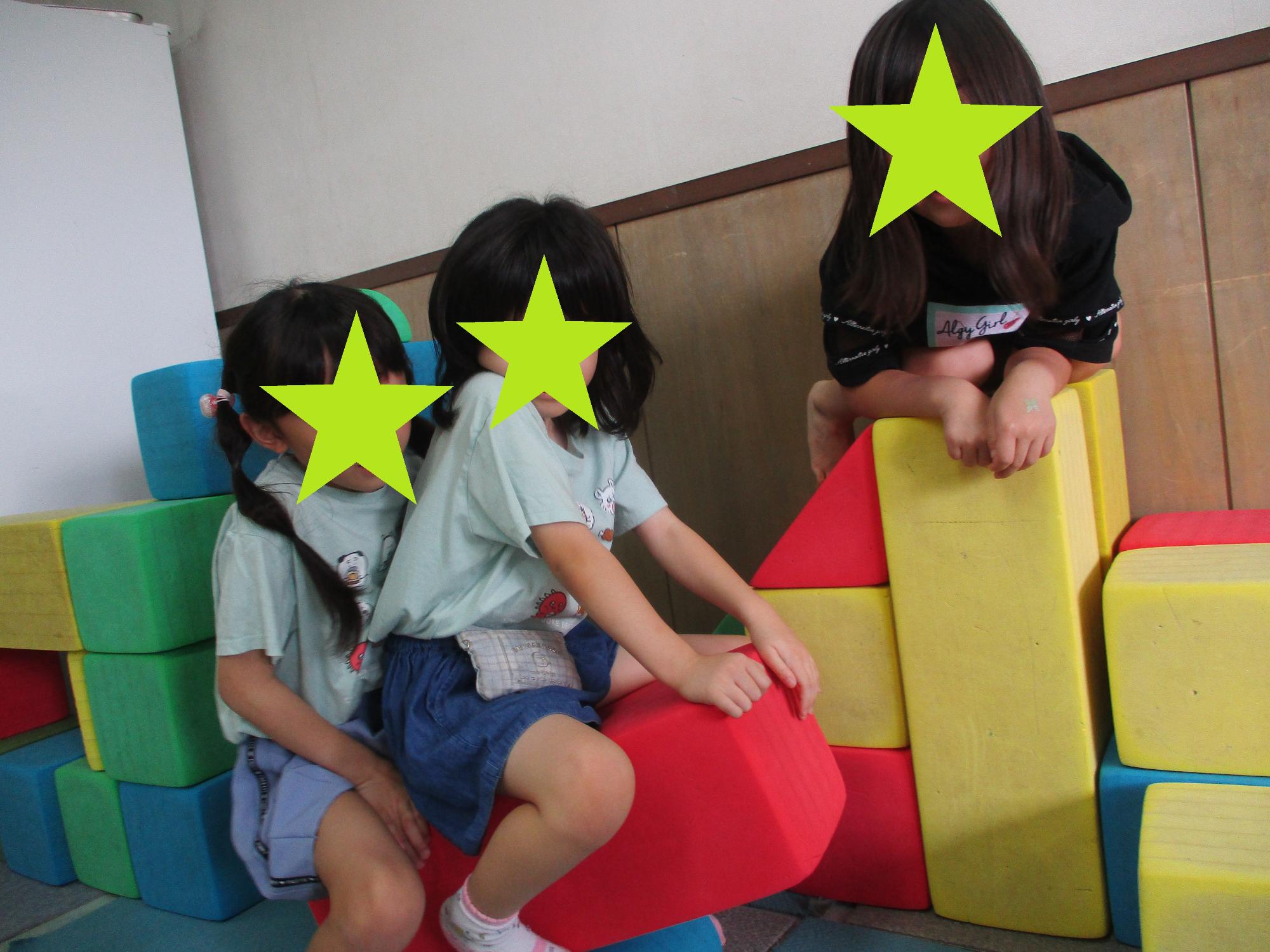 大きいブロックに乗って遊ぶ3人の子