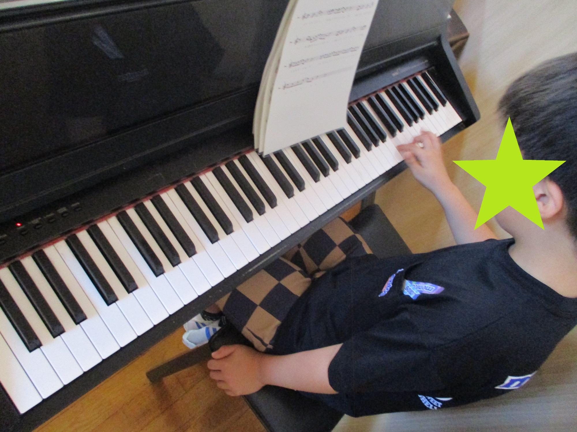 楽譜を見ながらピアノの練習をする子
