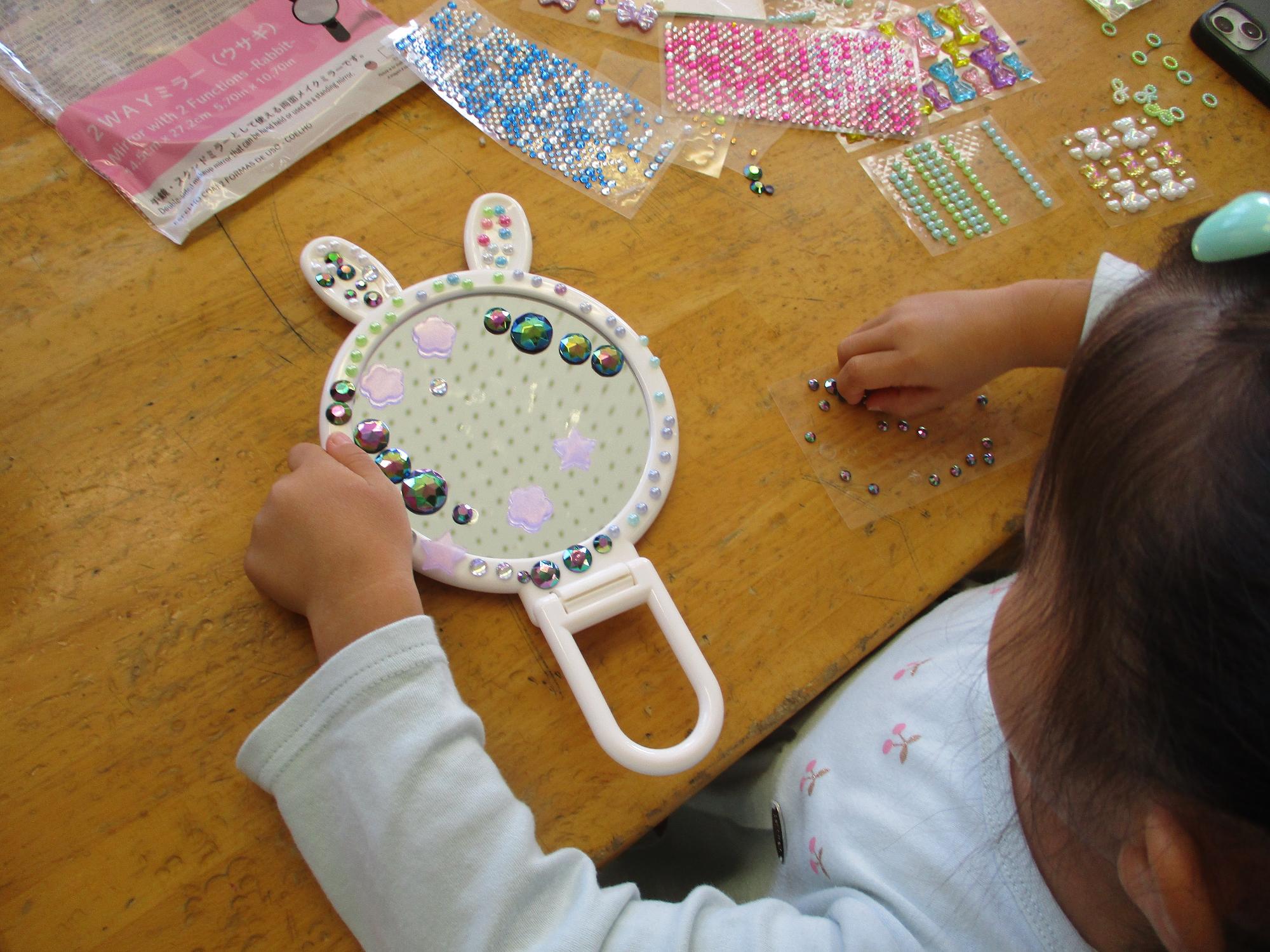 ミラーにキラキラシールを貼る女の子