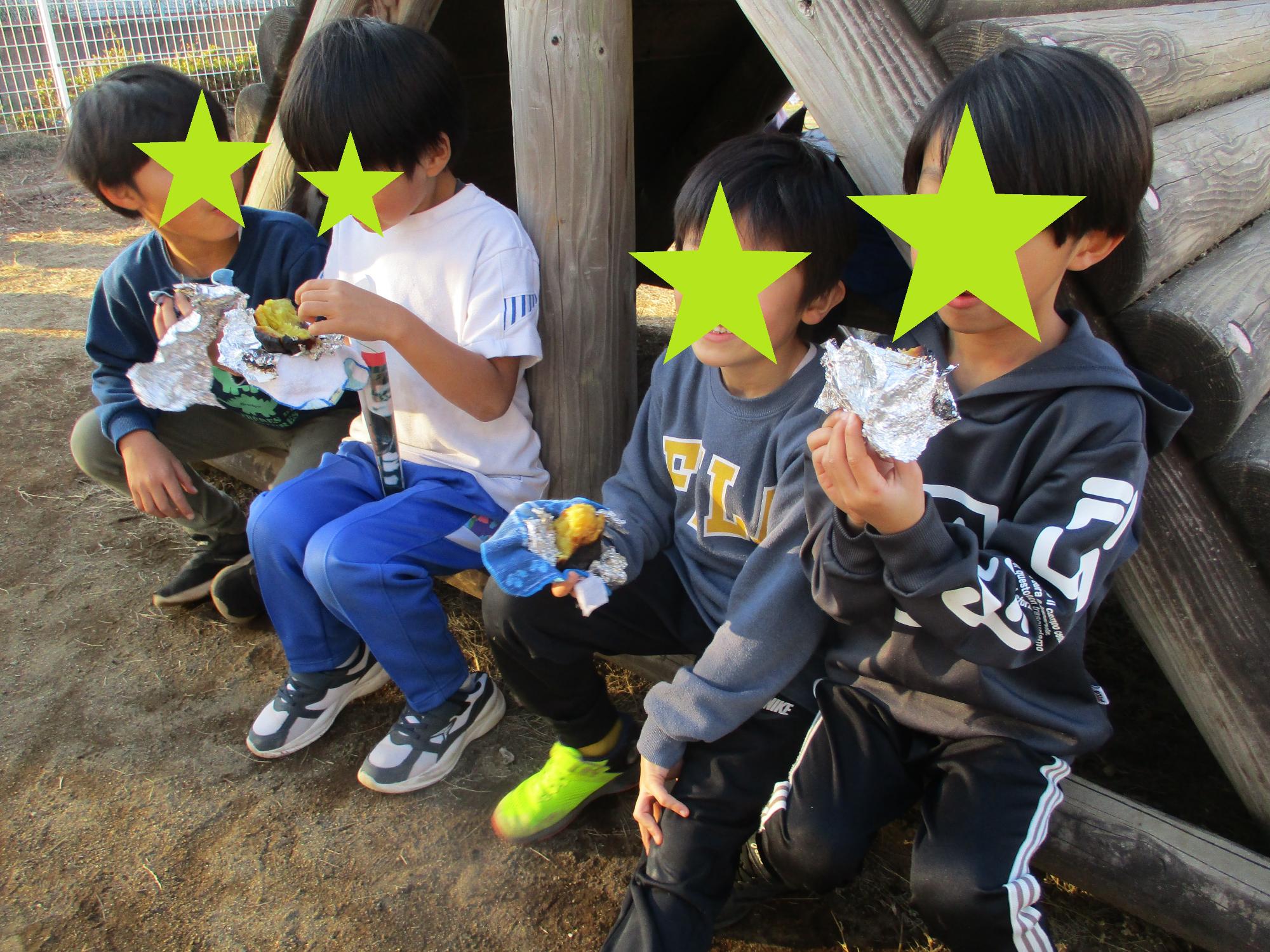 遊具に座って焼き芋を食べる4人の子