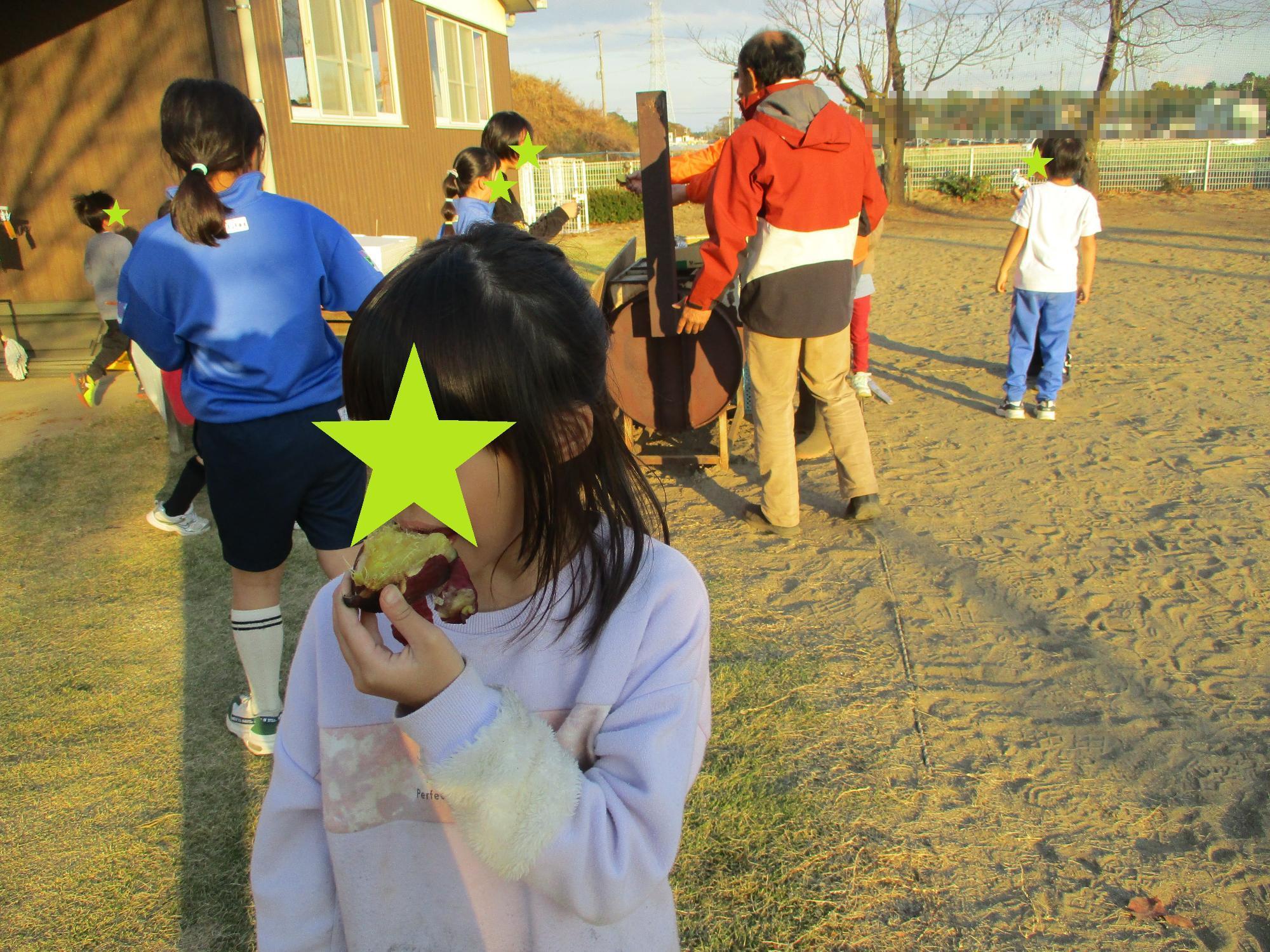 焼き芋機の周りで焼き芋を食べる子どもたち