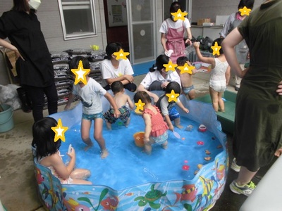 水着を着た子供たちが小さなプールに入って遊んでいる写真
