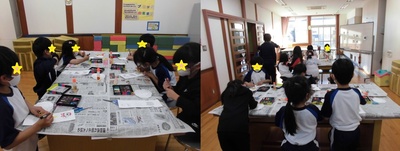 机一面に敷かれた新聞紙の上で紙に色を塗っていく子供たちの写真