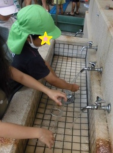 子どもたちが水道でシャボン玉セットを洗っている写真
