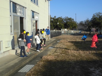 児童センターの外に出た子どもたちが2つの鬼に向かって豆をまいている写真