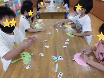 子どもたちが壁面に飾るための紙の傘を作っている様子