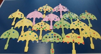 壁面に飾る色とりどりの紙の傘を机に並べている写真