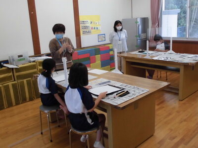 書道体験にて、教室で先生が子どもたちに教えている様子の写真