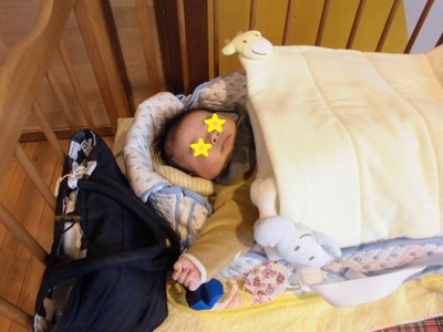 ベビーベッドで寝かせられるあかちゃんの写真