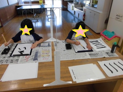 2人の子どもが書道の練習をしている写真