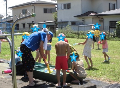 先生と一緒に水遊びを楽しんでいる児童らの写真