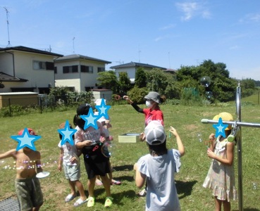 庭で空に向かってシャボン玉を作っている児童らの写真