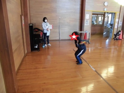 縄跳びの技を披露する子供と見守る先生の写真
