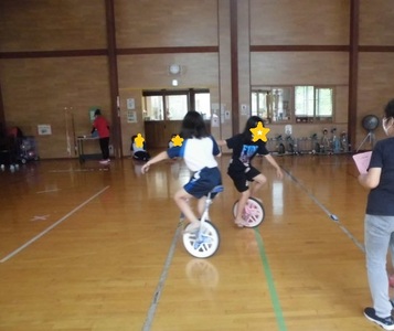 二人の子が手をつなぎ一輪車で回っている様子の写真