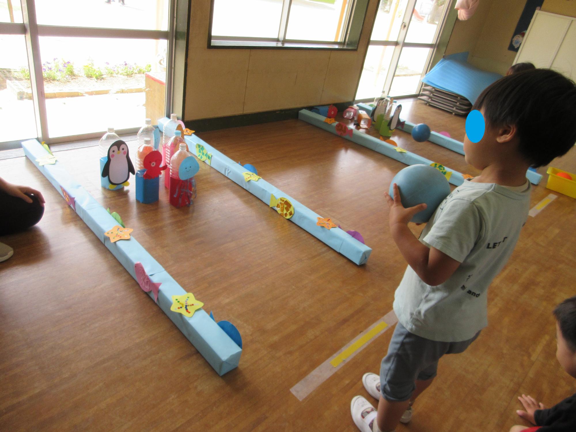 お部屋で子どもがペットボトルのボーリングをしています。
