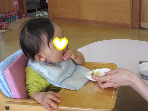 指でつまみ口に運び食べる0歳児
