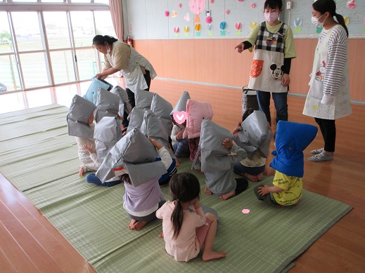 防災頭巾の被り方を練習する4歳児さくら組