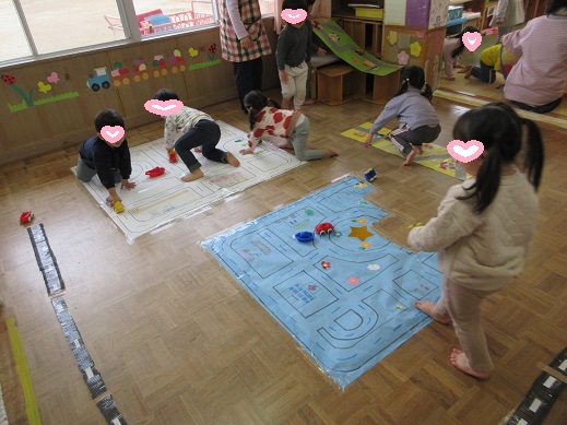 床一面に大きな道路を作り、たくさんの車を走らせるこどもたち