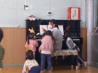 保育士のピアノに集まる子どもたち