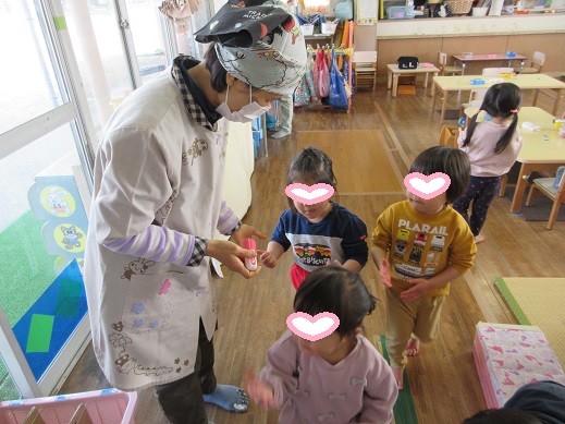 手洗いチェックのスタンプを押してもらい笑顔を見せるもも組の子どもたち