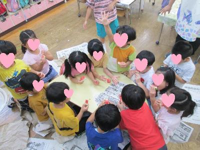 テーブルを囲んでスイカを食べる子どもたち