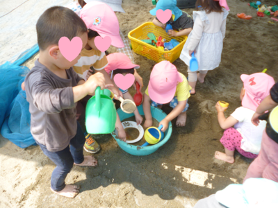 子どもたちがバケツで砂遊びをしたりじょうろで水をまいている写真