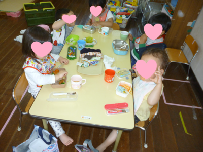 子どもたちがテーブルに座りお弁当を広げている写真