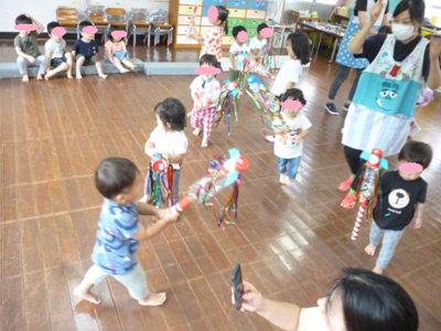 子どもたちが飾りのついた棒を持ちながら歩き回っている写真