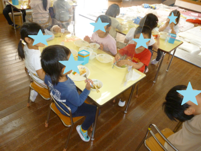 子どもたちがテーブルに座って給食を食べている写真