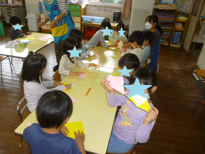 子どもたちがテーブルに座って折り紙を折っている写真