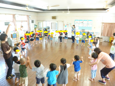 子どもたちと先生たちが輪になって踊っている写真