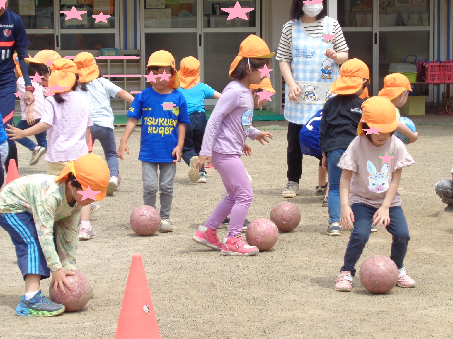 ボールを地面においたり、足でサッカーボールを蹴る子どもたち」