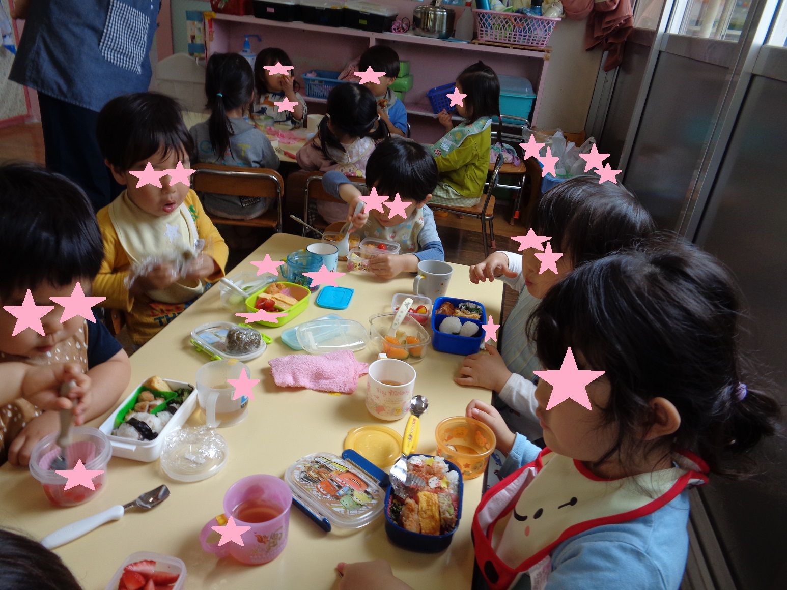 テーブルを囲みお弁当箱を開けて食べる子どもたち