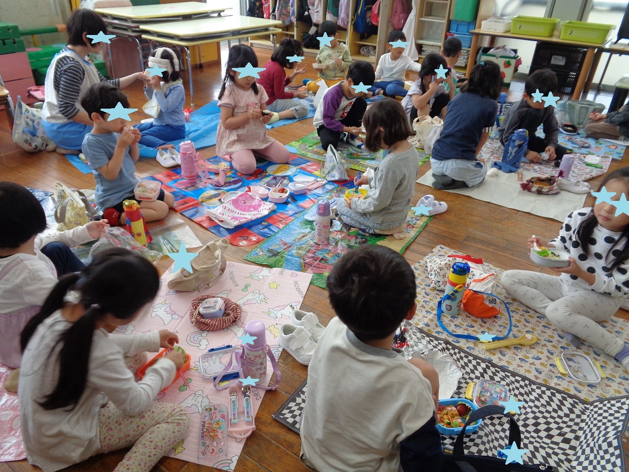 シートを広げその上に座りお弁当箱を開けて食べている子どもたち